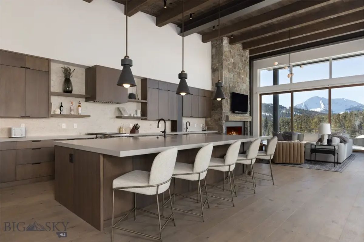 Sleek kitchen design includes dark wood cabinetry, a large island with barstool seating, and stylish pendant lighting.
