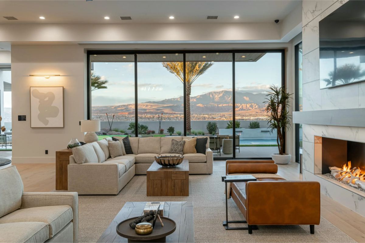 Open-concept living room with floor-to-ceiling glass doors overlooking a desert mountain landscape.
