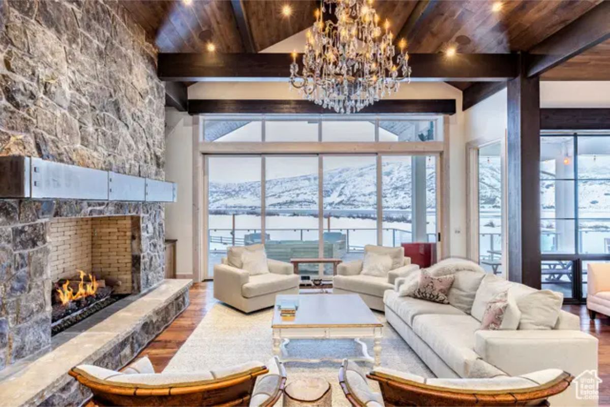 Large living area with floor-to-ceiling windows overlooking snow-covered mountains and a lake.