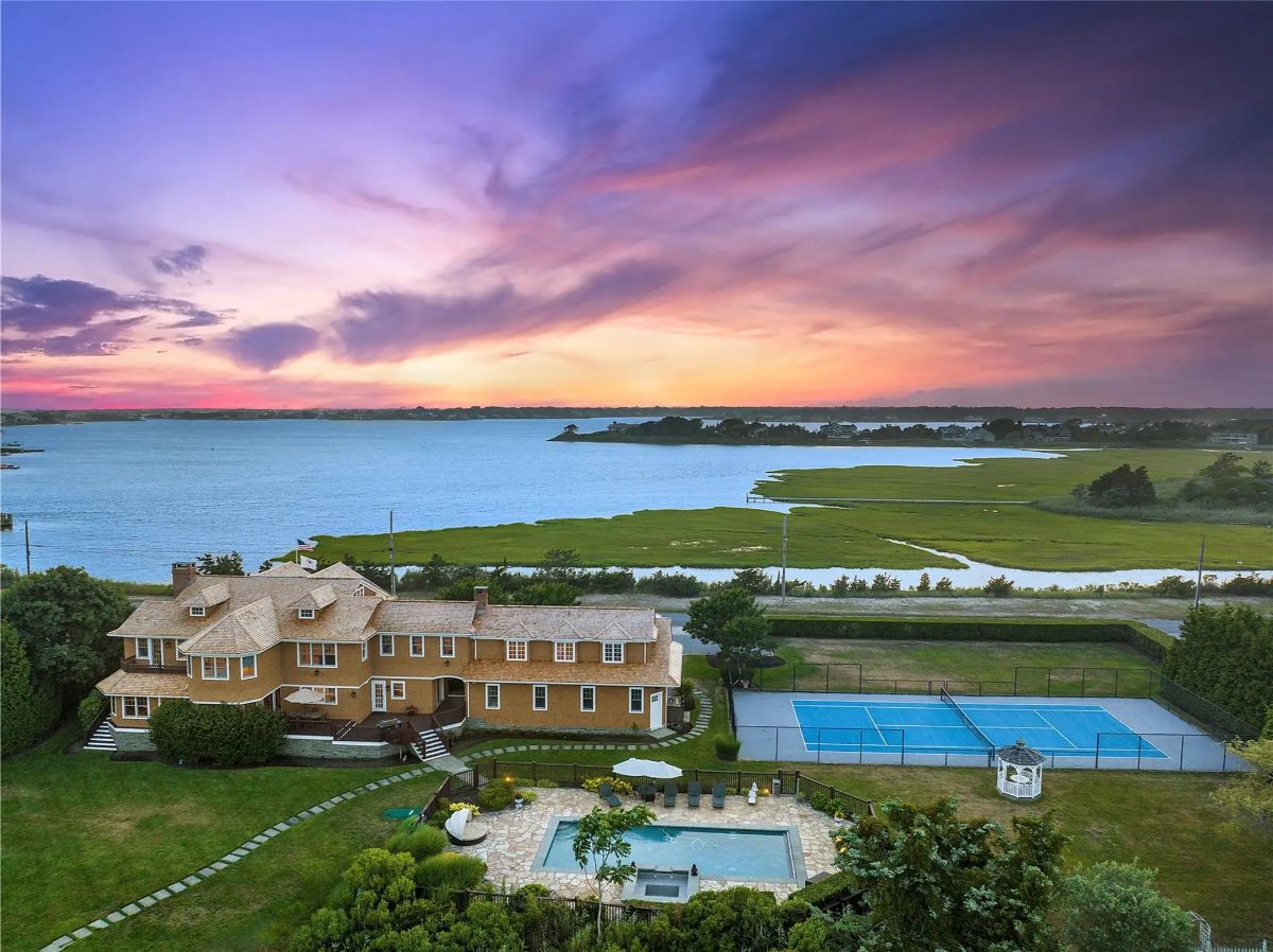 Large shingle-style home sits on a manicured lot facing open water and marshland.