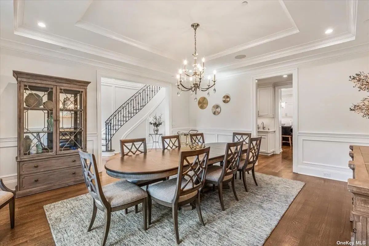 Oval dining table is surrounded by eight wooden chairs on a textured rug.