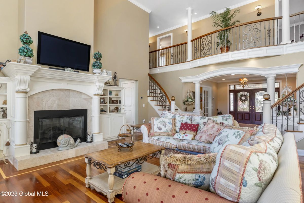 Double-height ceiling opens up to a second-floor balcony with decorative railing.