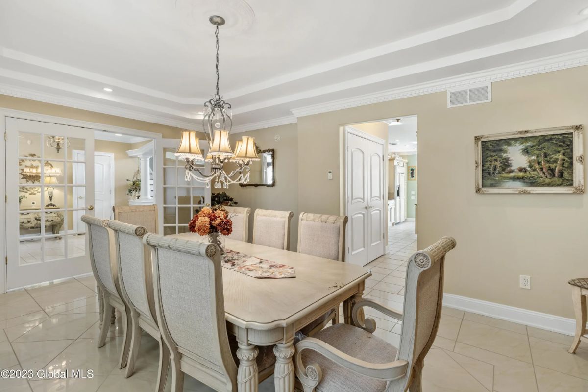 Rectangular table with seating for eight sits beneath a tiered chandelier.