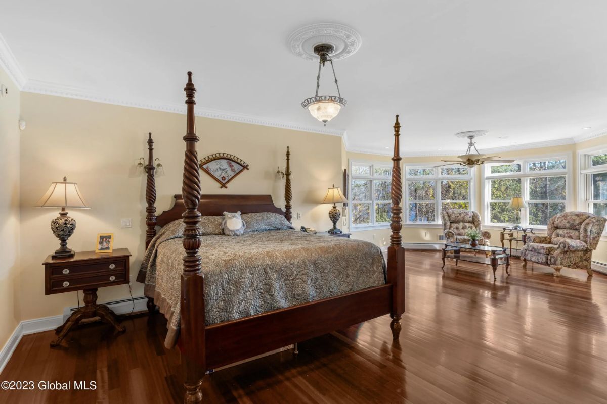 Wood bed with tall posts anchors the space between matching nightstands.