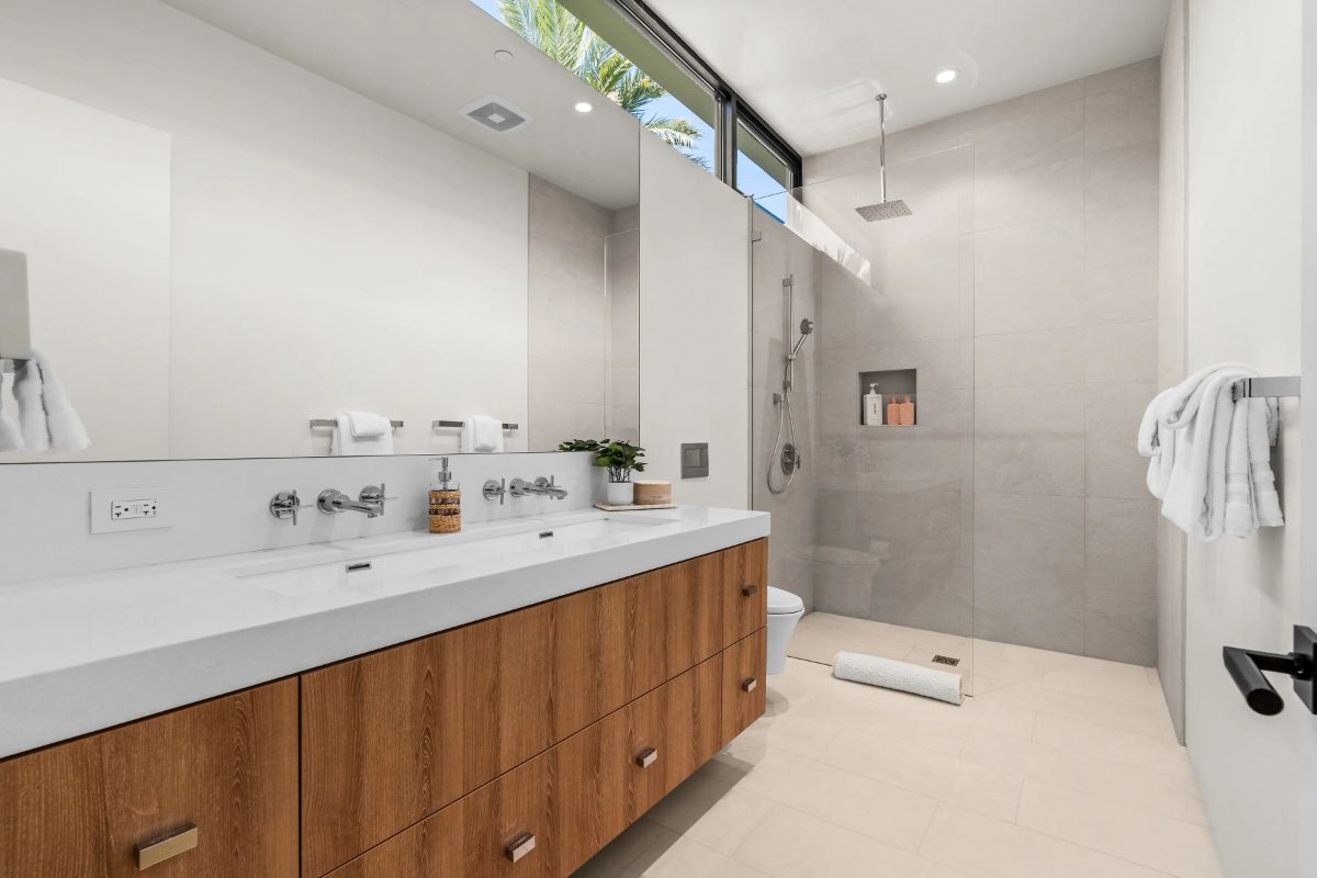 Floating vanity stretches the length of one wall with two sinks and wood cabinetry.