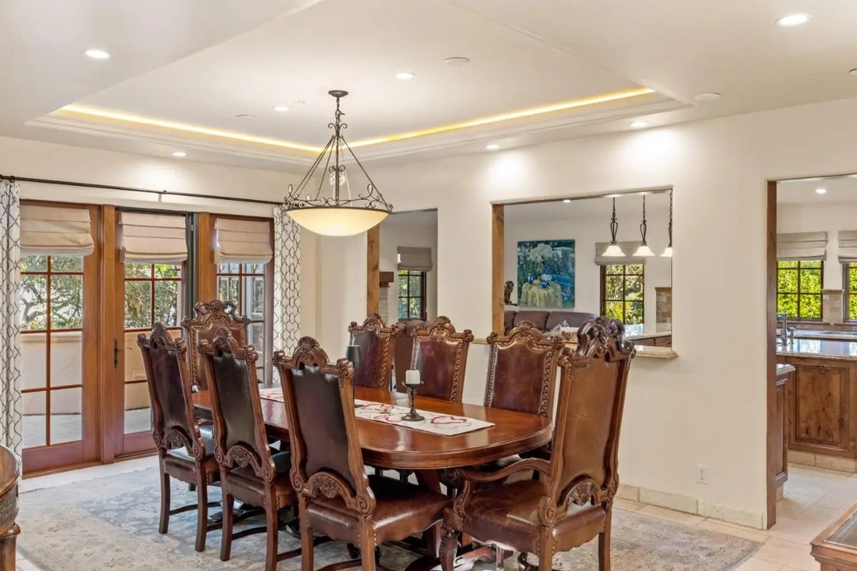 A rectangular wood table is surrounded by eight high-back carved chairs.