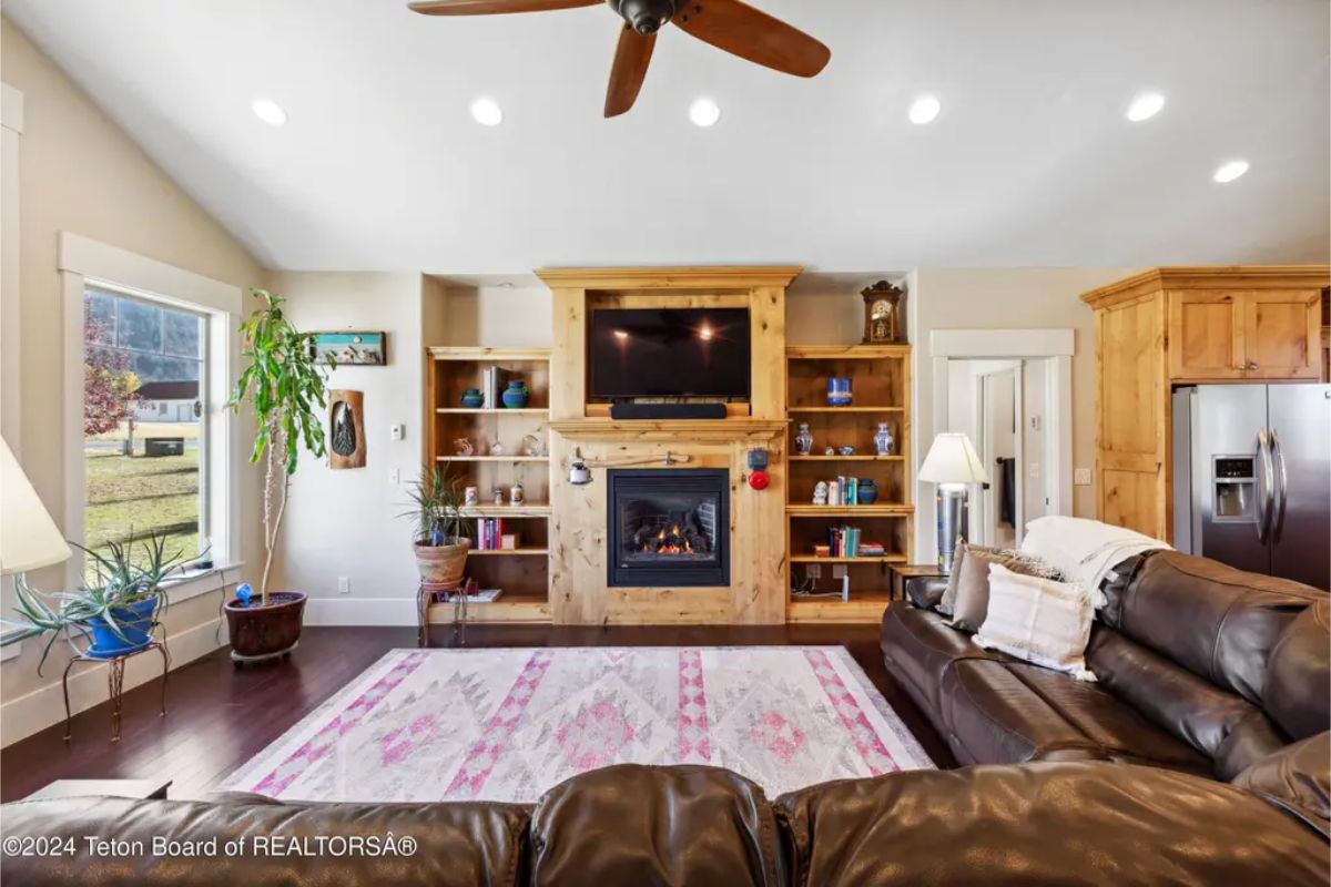 Built-in wooden shelving surrounds a central fireplace with a mounted television above it.
