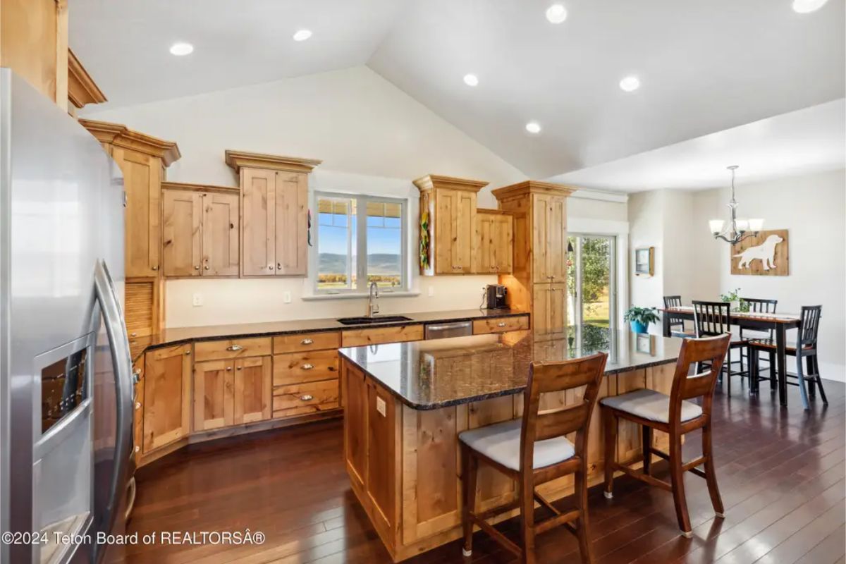 Wood cabinetry lines the walls, paired with stainless steel appliances and dark granite countertops.
