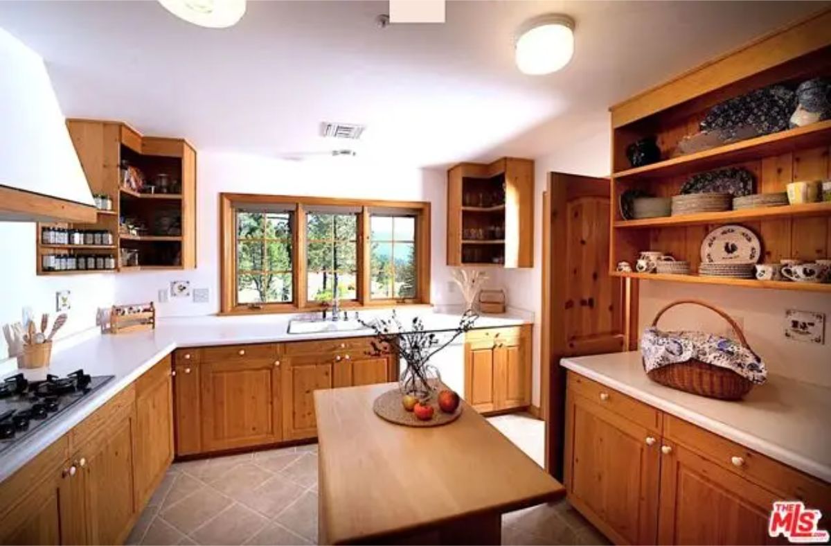 Wraparound wooden cabinetry lines the walls under white countertops.