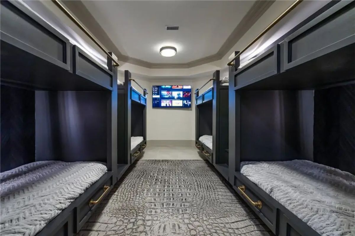 Spacious bunk room with four built-in double bunk beds and a wall-mounted TV. 