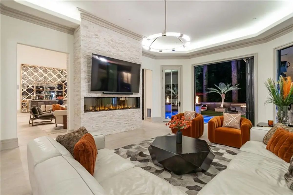 Chic family room featuring a linear fireplace, mounted TV, and luxurious seating with views of the backyard. 