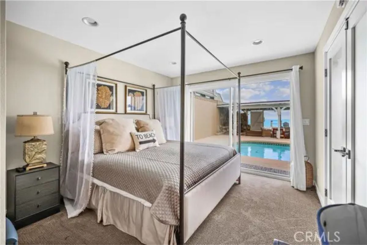 Four-poster bed faces sliding glass doors that open to the pool area.