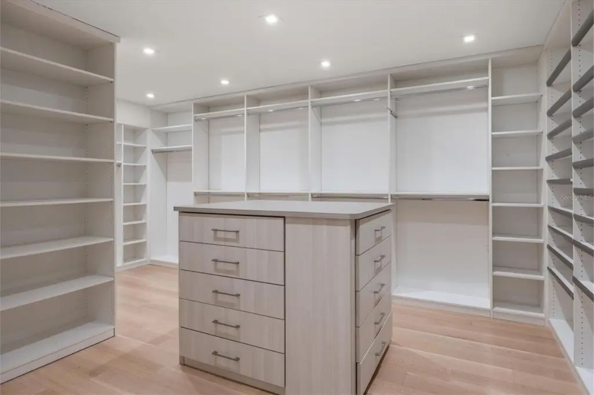 Spacious walk-in closet with ample shelving, built-in drawers, and modern recessed lighting. 