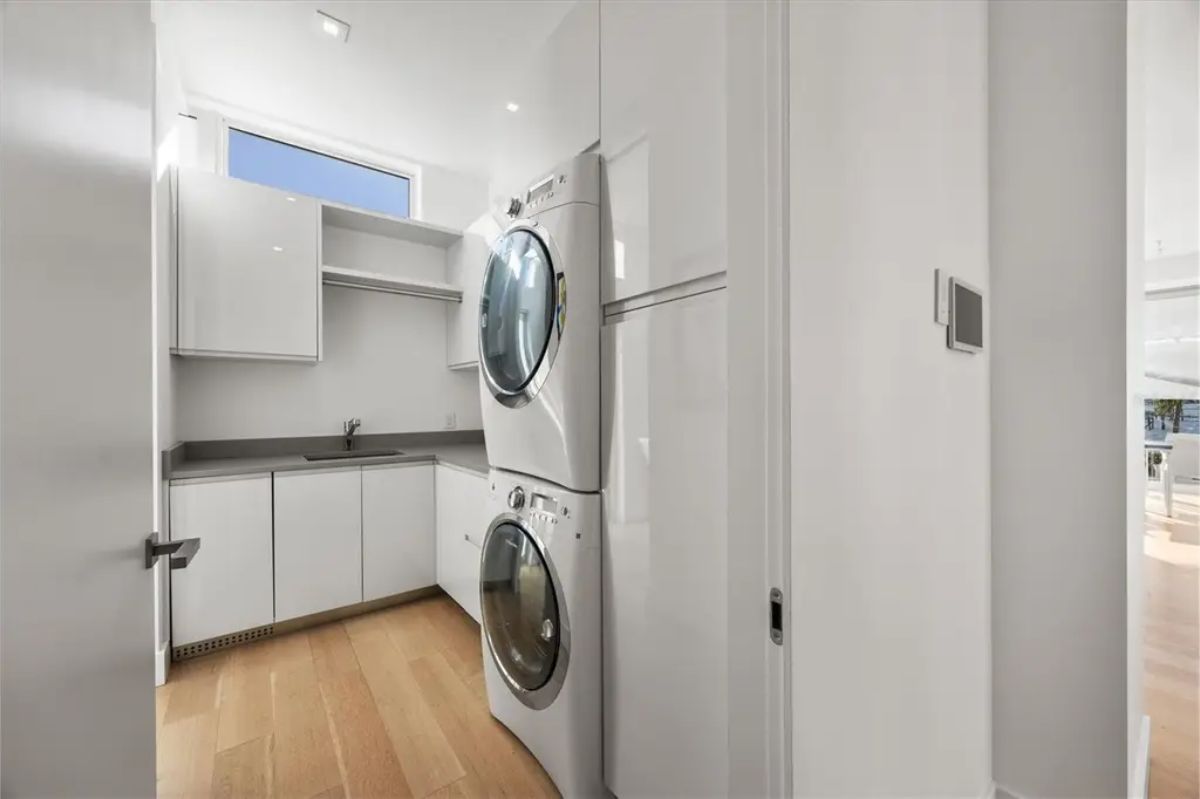 Compact yet functional laundry room with stacked washer and dryer, white cabinetry, and a sleek design. 