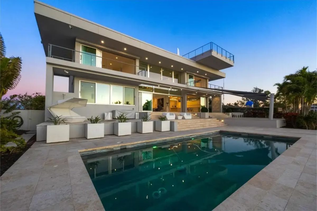 Striking pool area with contemporary architecture, warm evening lighting, and a spacious deck. 