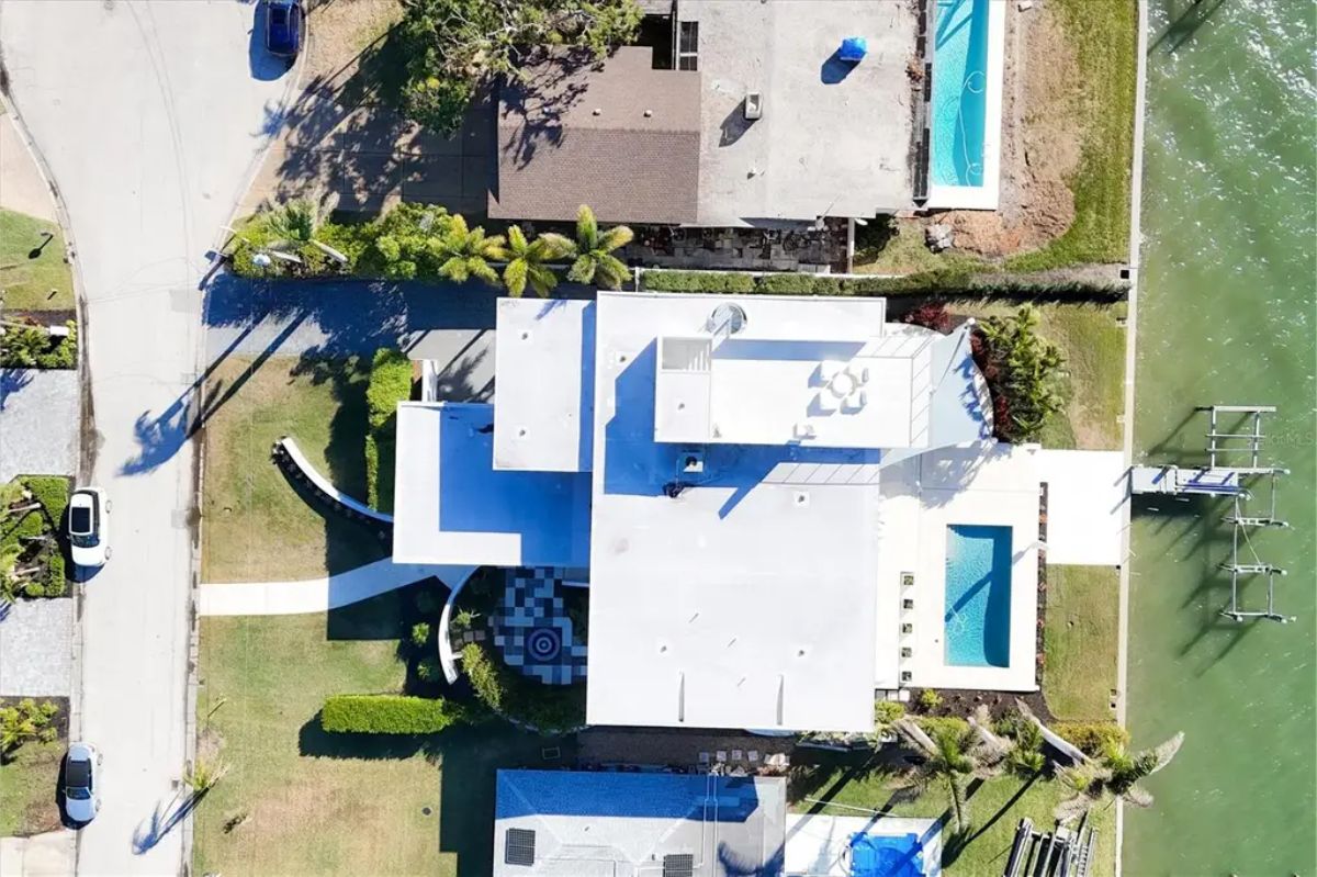 Aerial view of the waterfront property showcasing its modern design, pool, and private dock. 