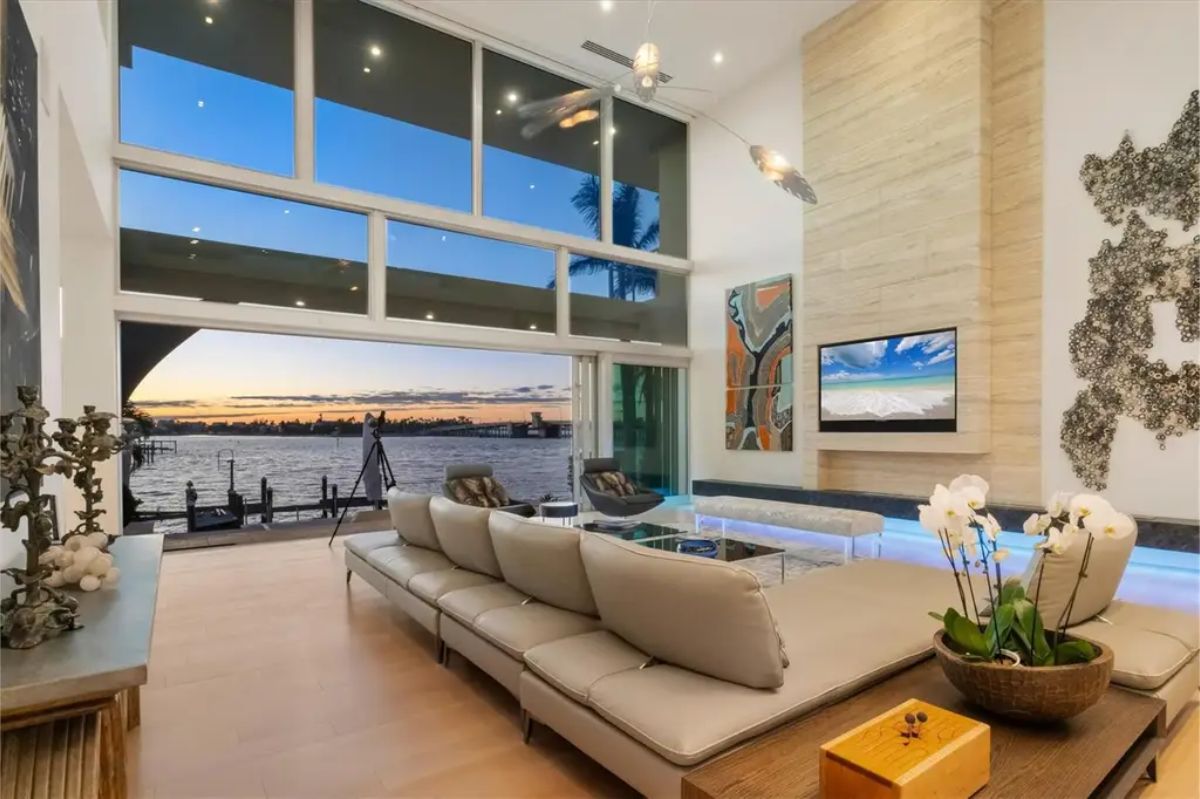 Cozy yet modern living space with floor-to-ceiling glass, warm lighting, and a scenic sunset view. 