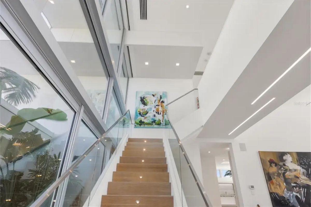 Stylish staircase with glass railings, modern lighting, and vibrant artwork accenting the space. 