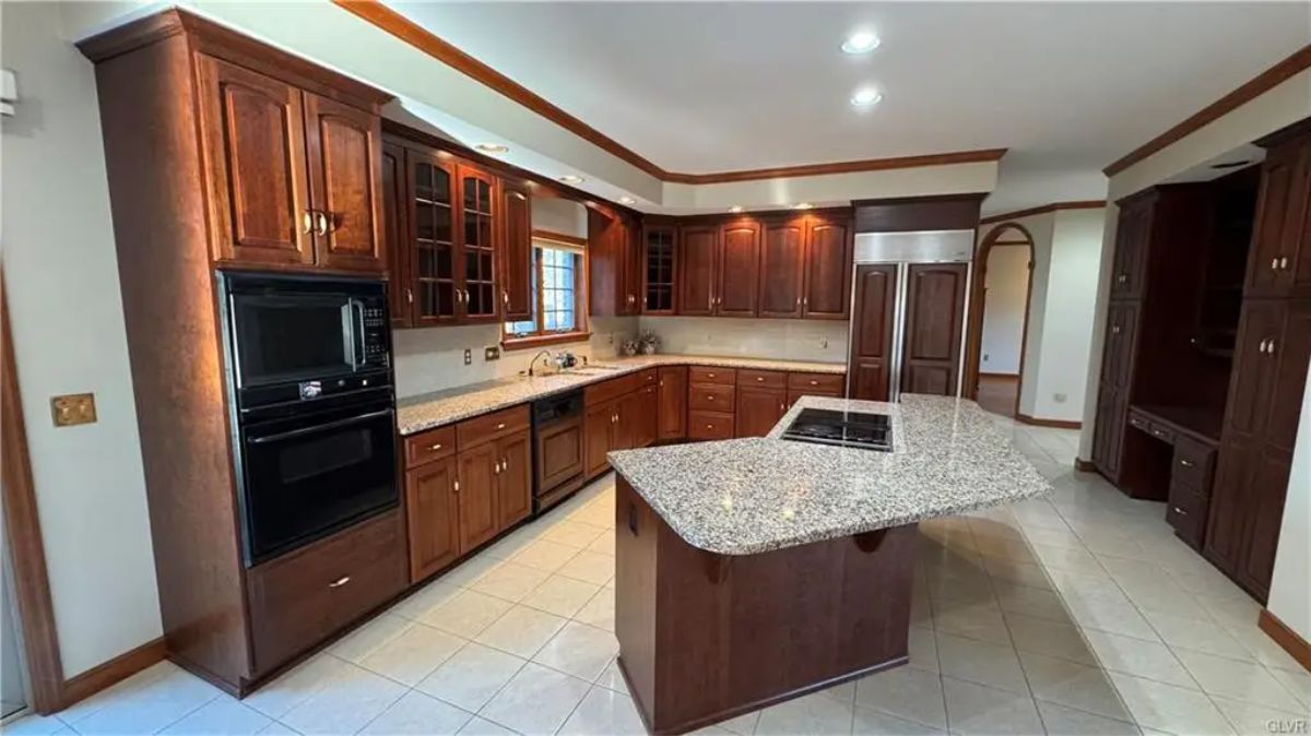 Dark wood cabinets extend throughout the kitchen with glass panel inserts on upper sections.