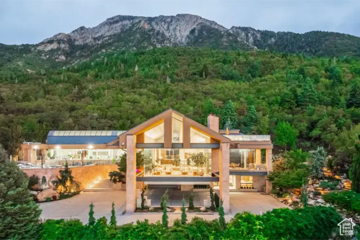 Magnificent modern mountain home with a striking A-frame design, set against a lush, green hillside.