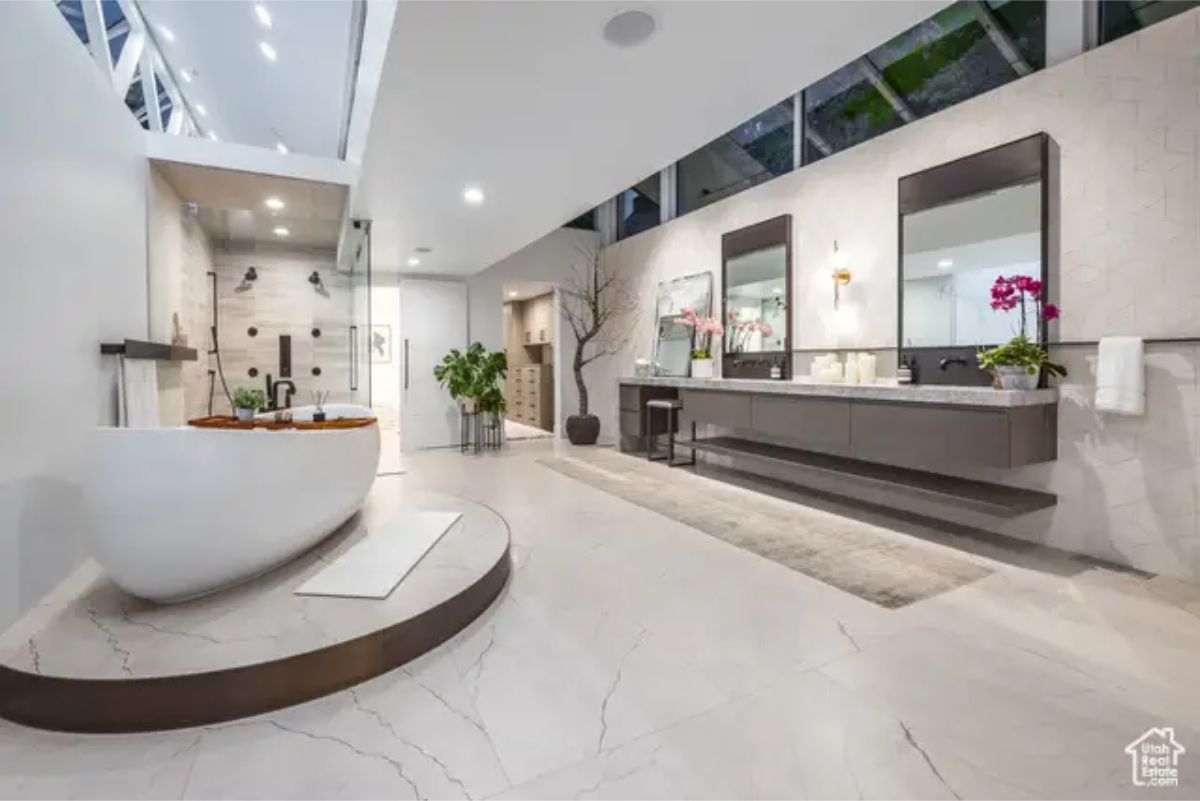 A spacious bathroom featuring a floating vanity, dual sinks, and sleek marble flooring with natural light from large windows. 
