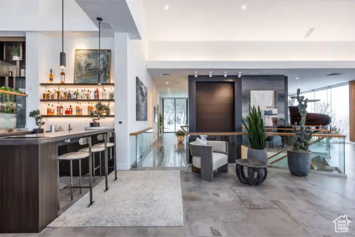 A sophisticated home bar with a dark wood counter, illuminated liquor display, and comfortable seating in a contemporary space. 