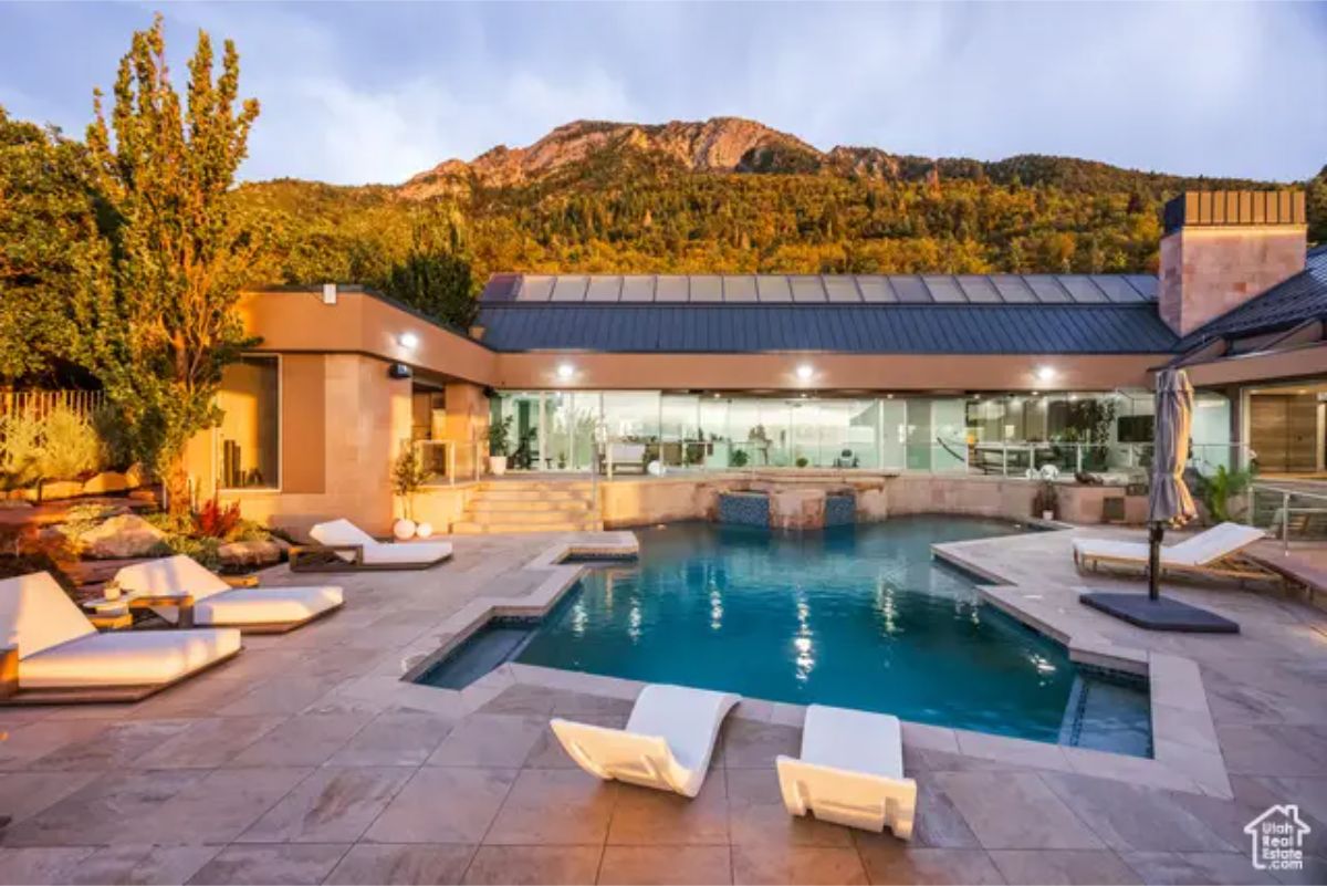 A stunning pool area with mountain views, surrounded by lounge chairs and modern architecture in the background. 