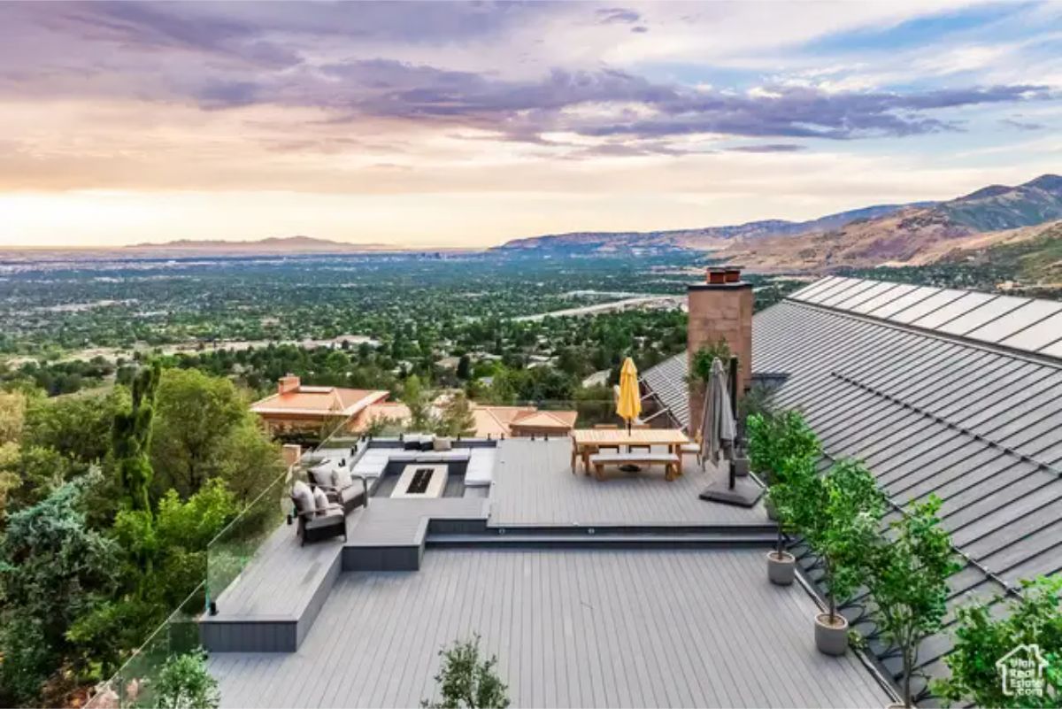 A breathtaking rooftop deck with a panoramic city and mountain view, featuring an outdoor seating and dining area. 
