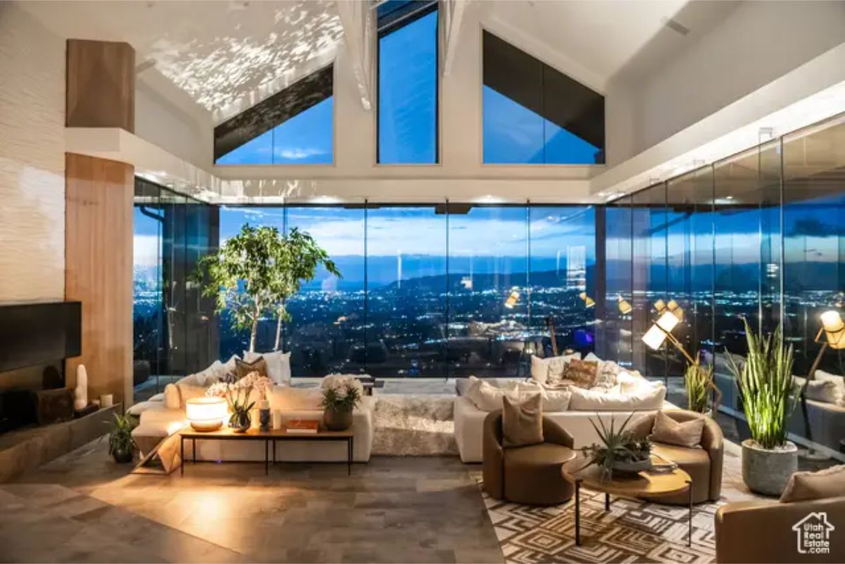 Cozy nighttime interior with a high vaulted ceiling, contemporary furniture, and stunning city lights in the background. 