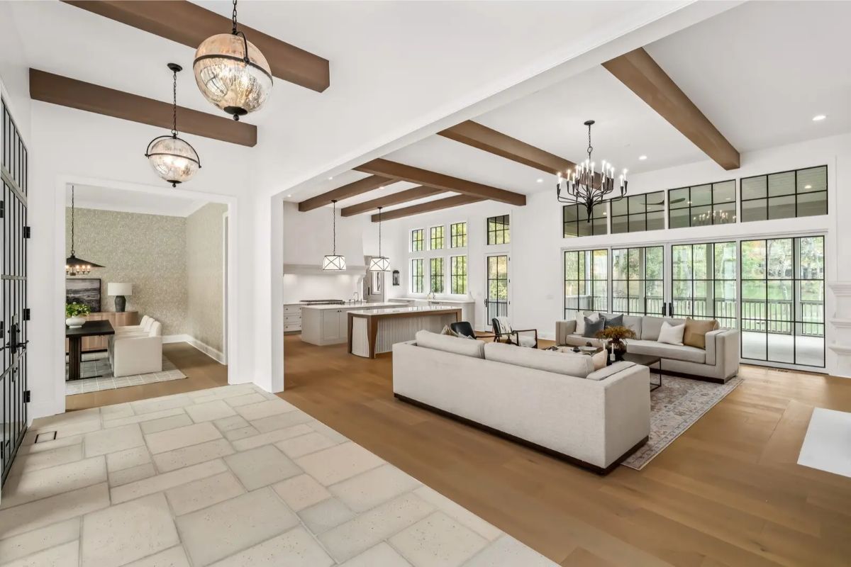 Open-concept main living area connecting kitchen and lounge, with rustic ceiling beams and abundant windows. 