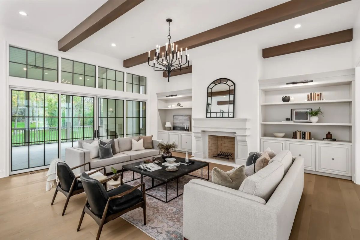 Sophisticated living room featuring dual sofas, a fireplace, built-in shelves, and large steel-framed windows. 