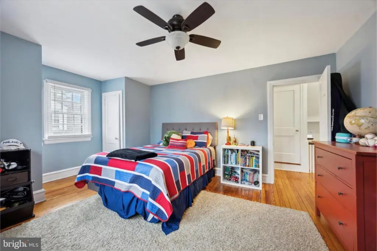 Spacious bedroom with a blue and red bedding set and a ceiling fan.