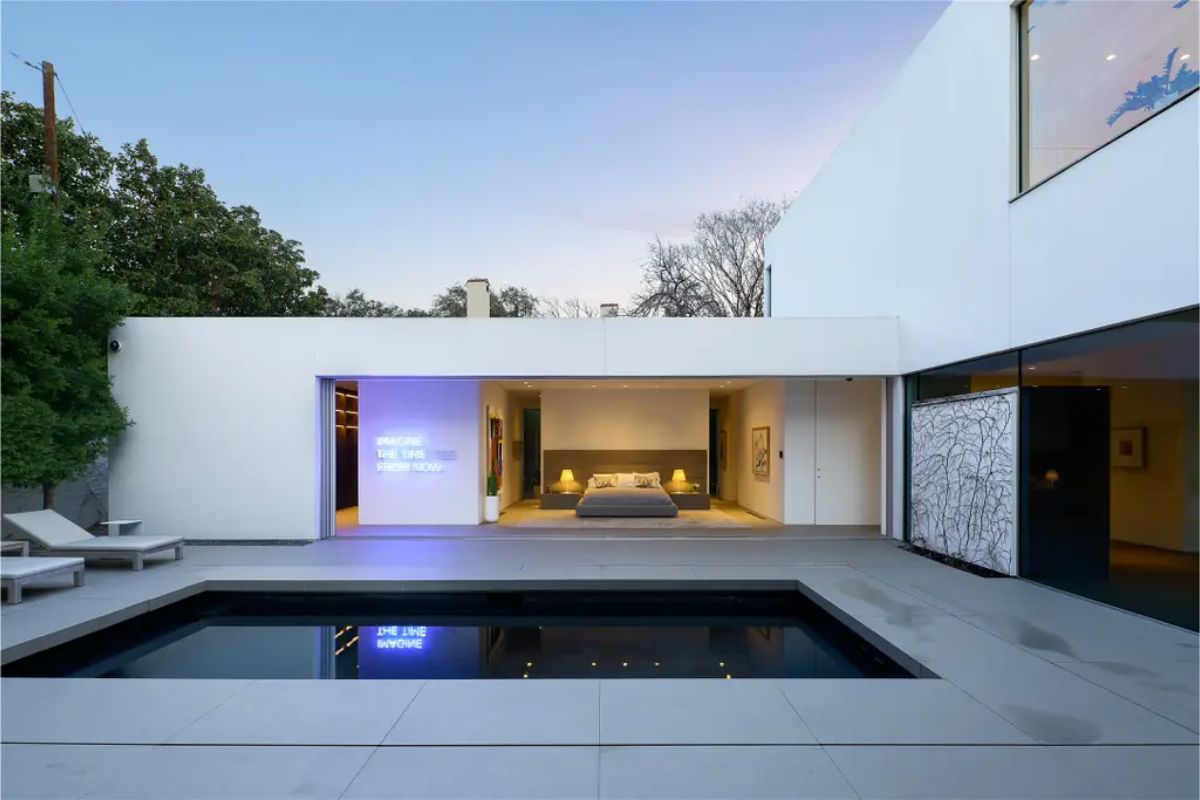 A stunning outdoor courtyard with a black-tiled pool and a bedroom opening directly onto it. 