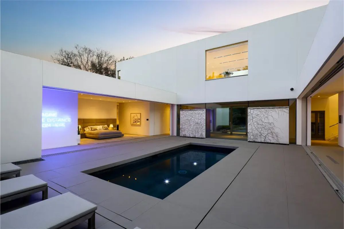 A nighttime view of the courtyard pool, framed by modern architecture and warm interior lighting. 