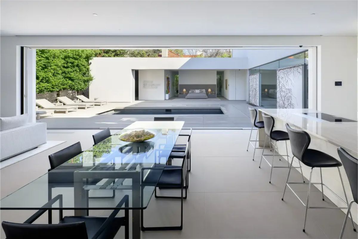 Spacious dining and kitchen area with retractable walls opening to a luxurious outdoor pool. 