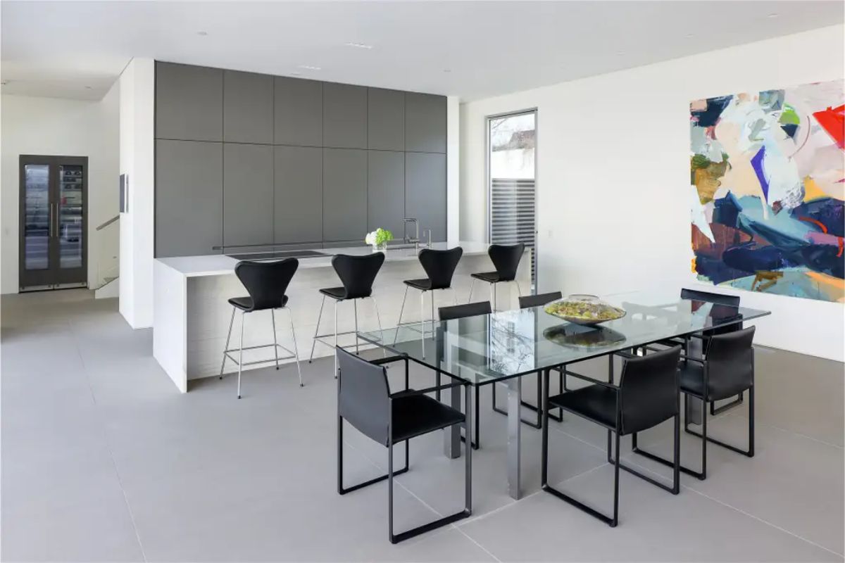 Elegant dining space featuring a glass table, black chairs, and a striking abstract painting. 