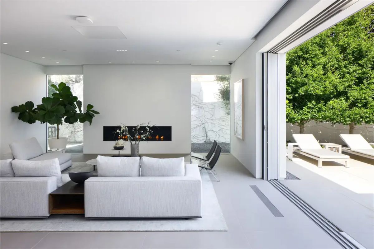 Open-concept living room seamlessly connected to an outdoor patio with lounge chairs. 