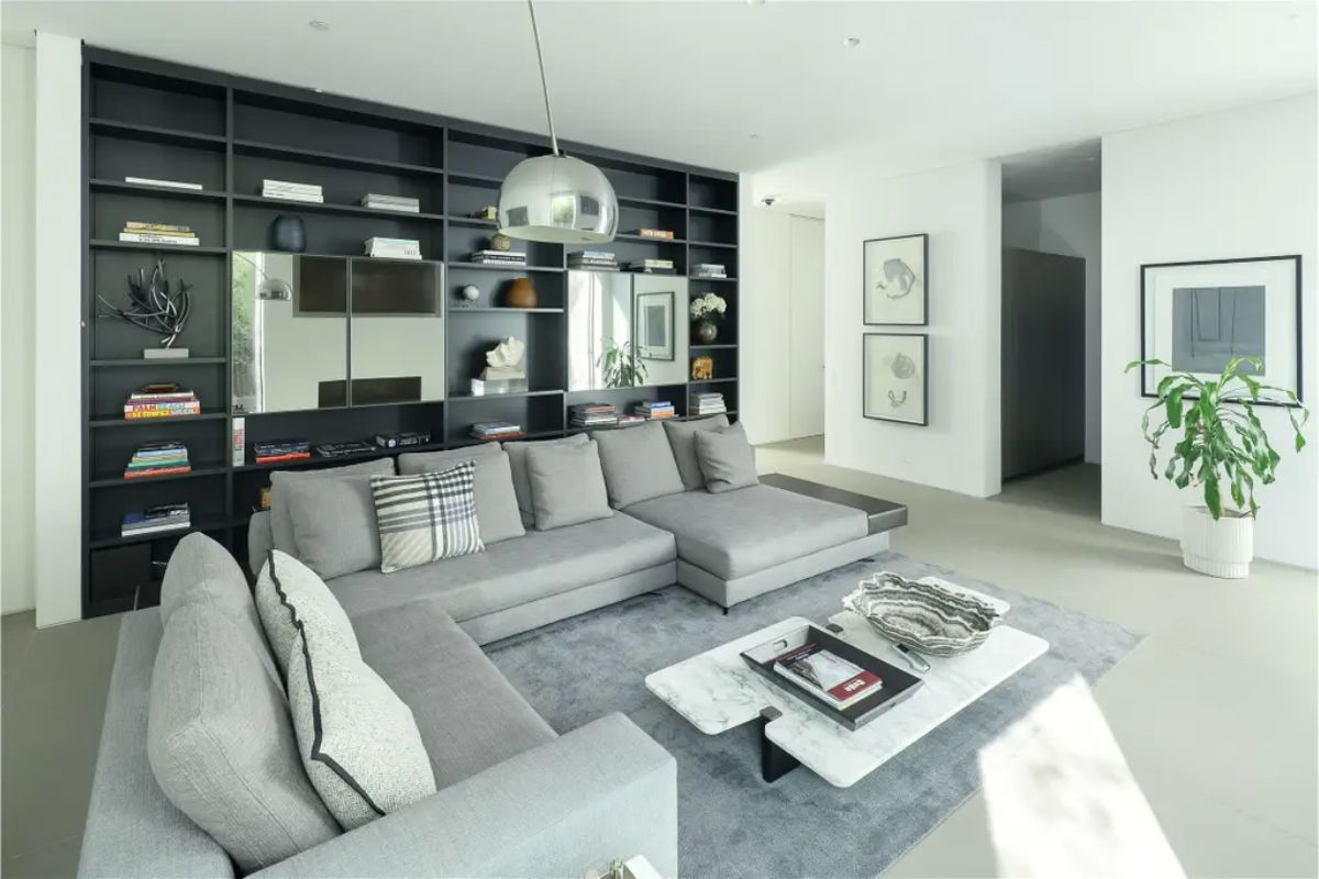 Stylish lounge area with a large sectional sofa, a built-in bookshelf, and modern decor. 