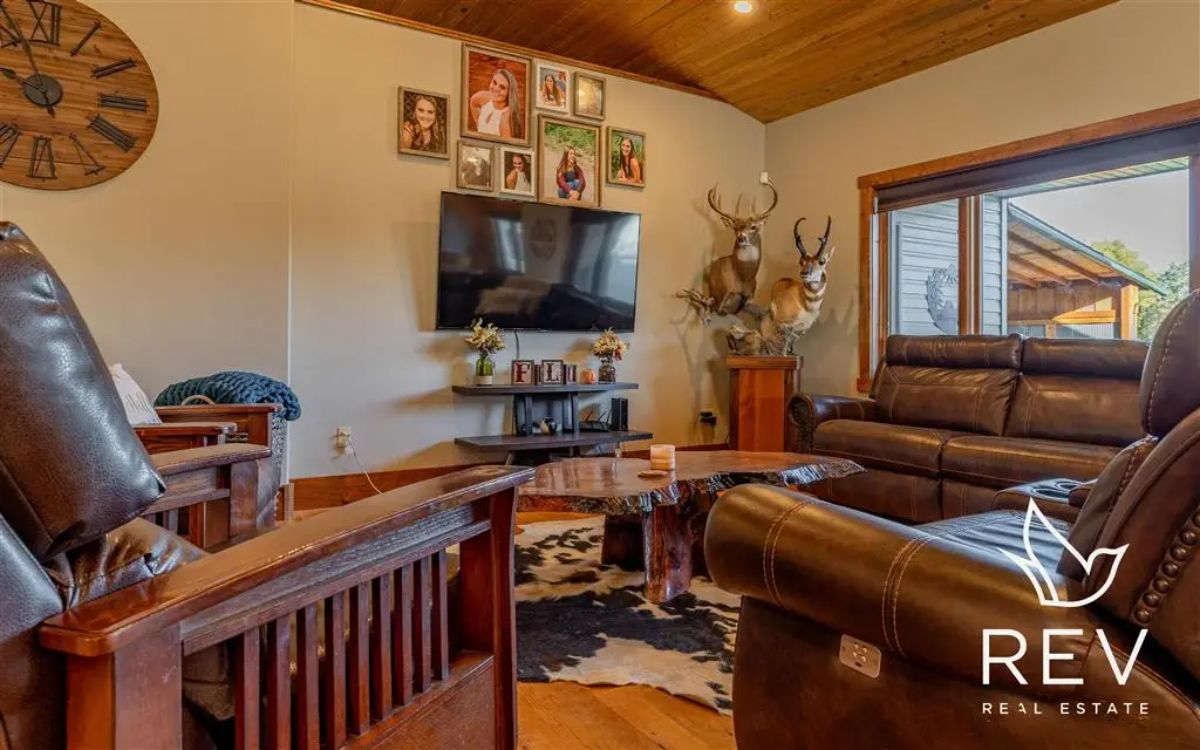 Leather recliners and wooden armchairs surround a mounted television.