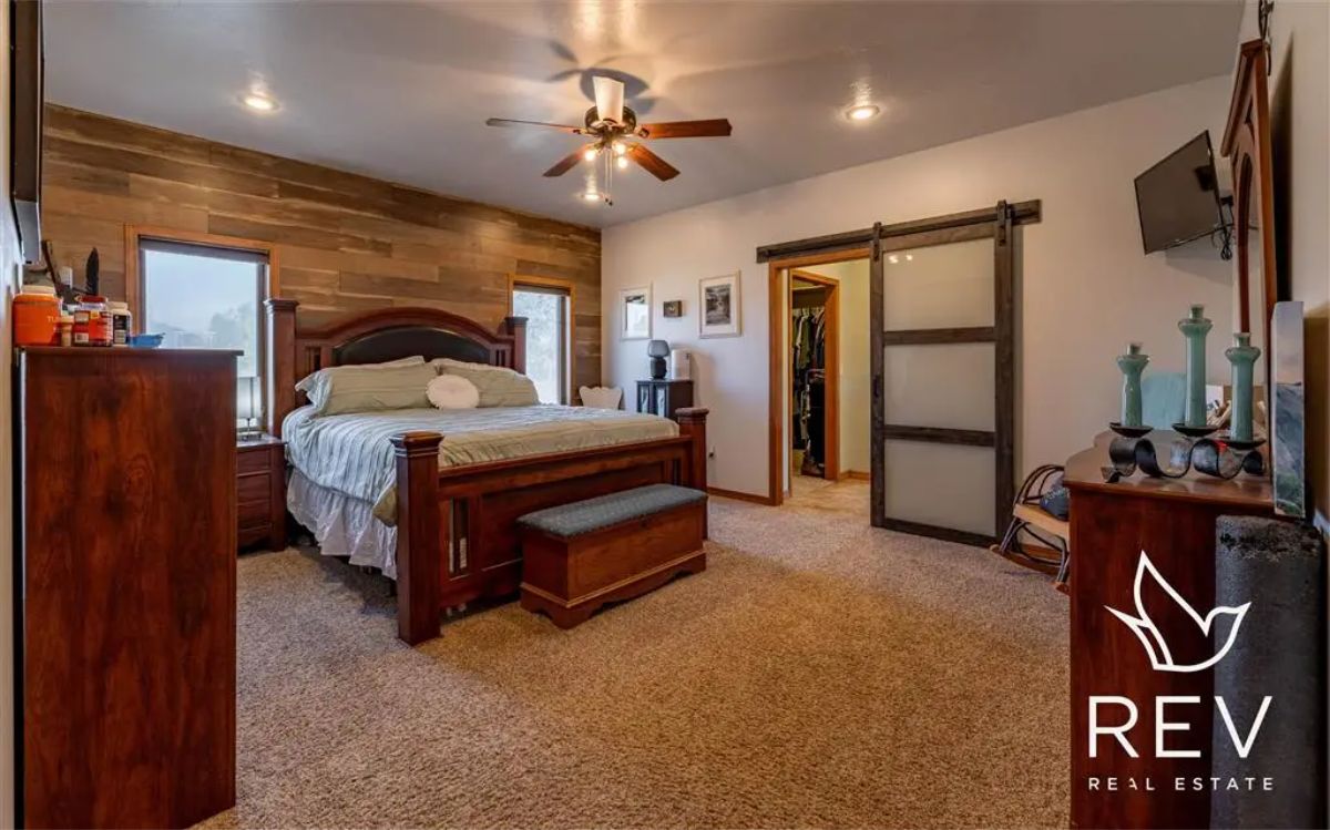 A large wooden bed is positioned against a plank-accented wall.