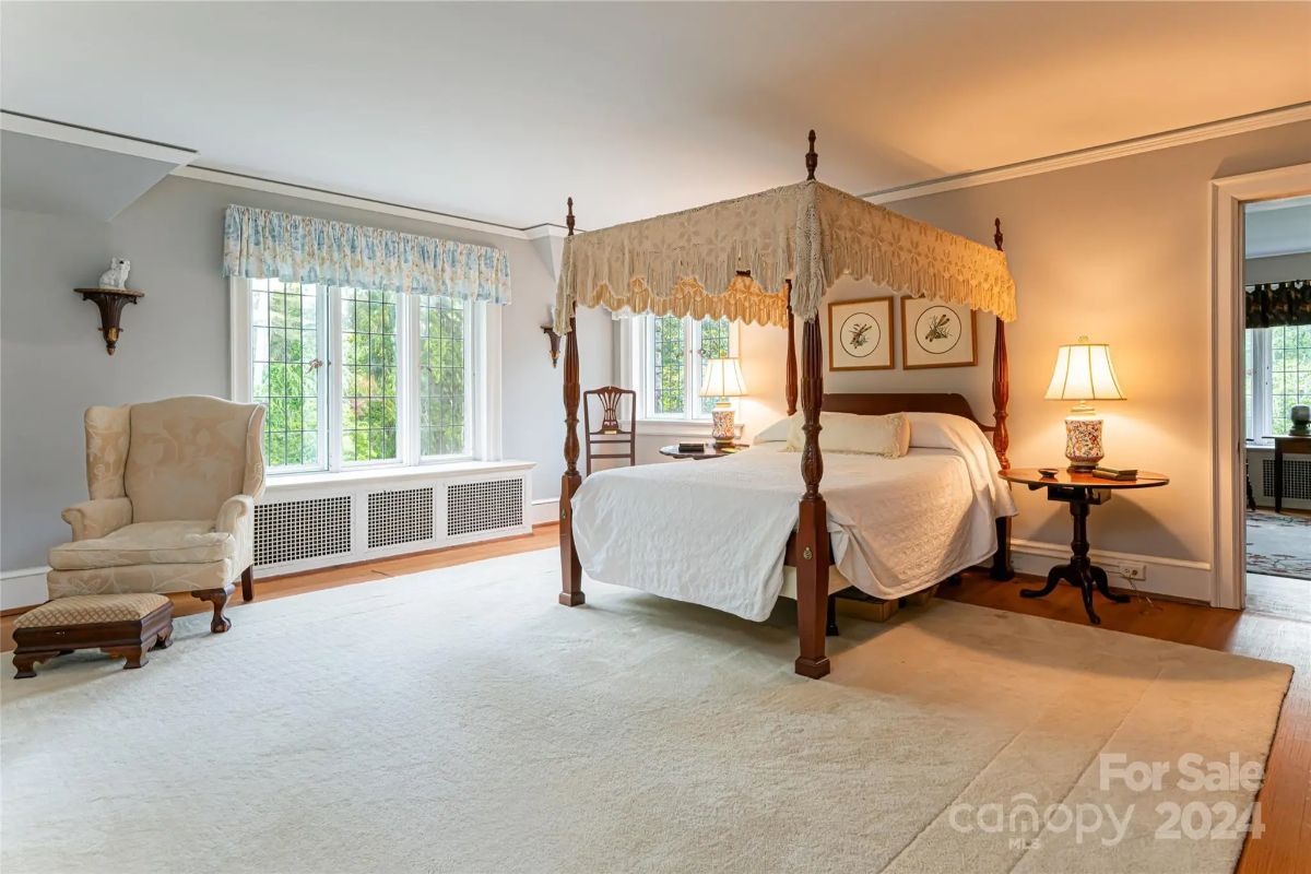 Four-poster canopy bed anchors the room with light carpet underfoot.