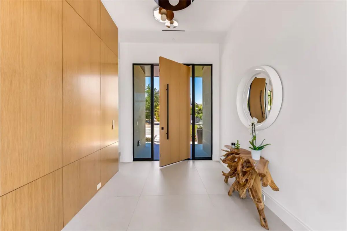 Minimalist entryway with a pivot front door, wooden paneling, and a rustic console table. 