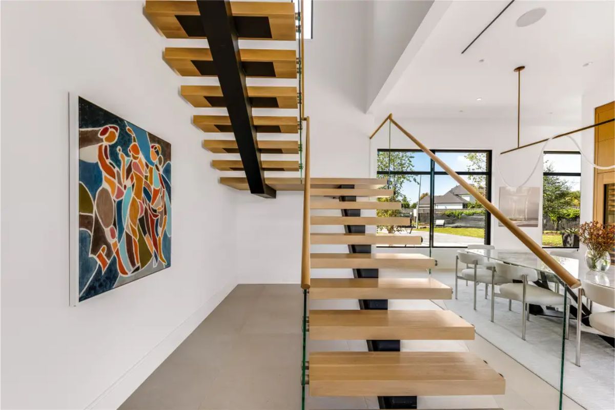 Close-up of the modern staircase showcasing its open design, metal support beam, and glass railing. 