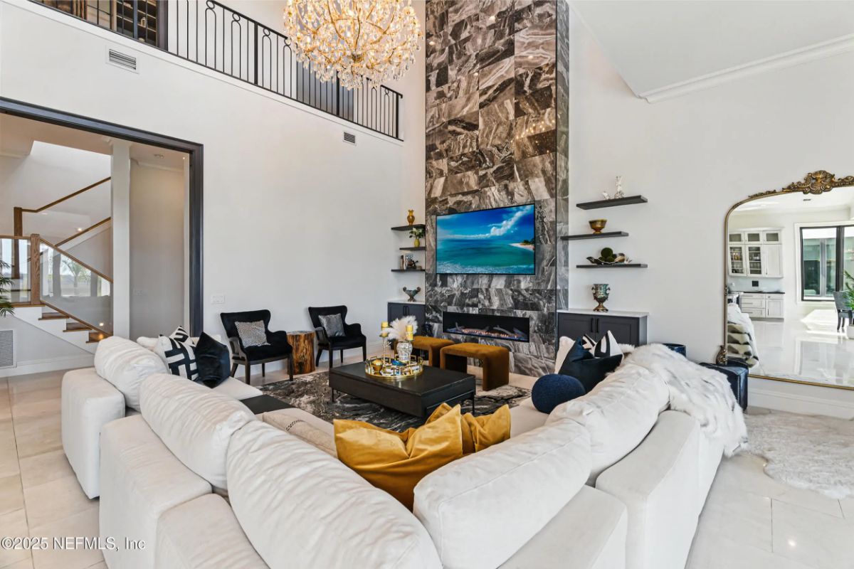 Double-height living room with a dramatic floor-to-ceiling stone accent wall and mounted TV.