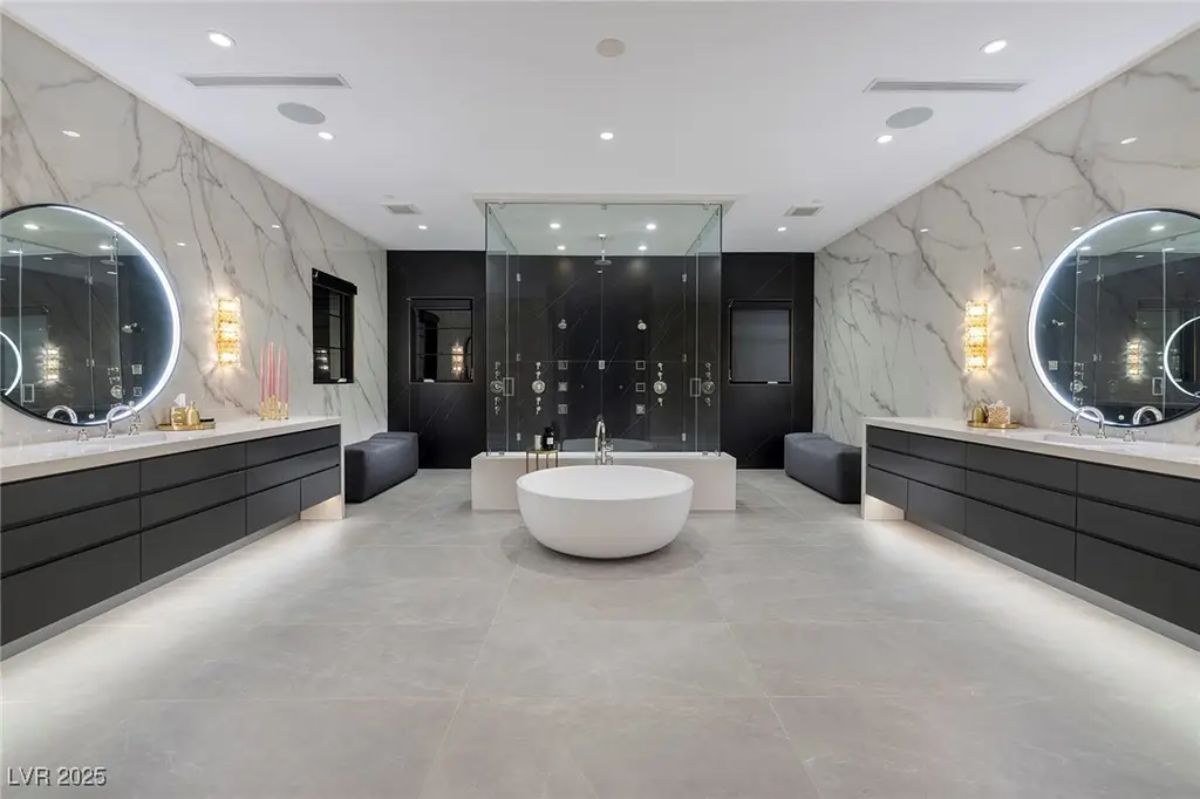 Bathroom with dual floating vanities and circular LED mirrors is designed with symmetry.