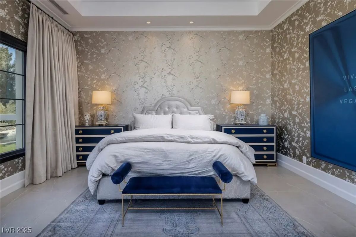 Guest bedroom with tufted headboard and patterned wallpaper incorporates deep blue accents.