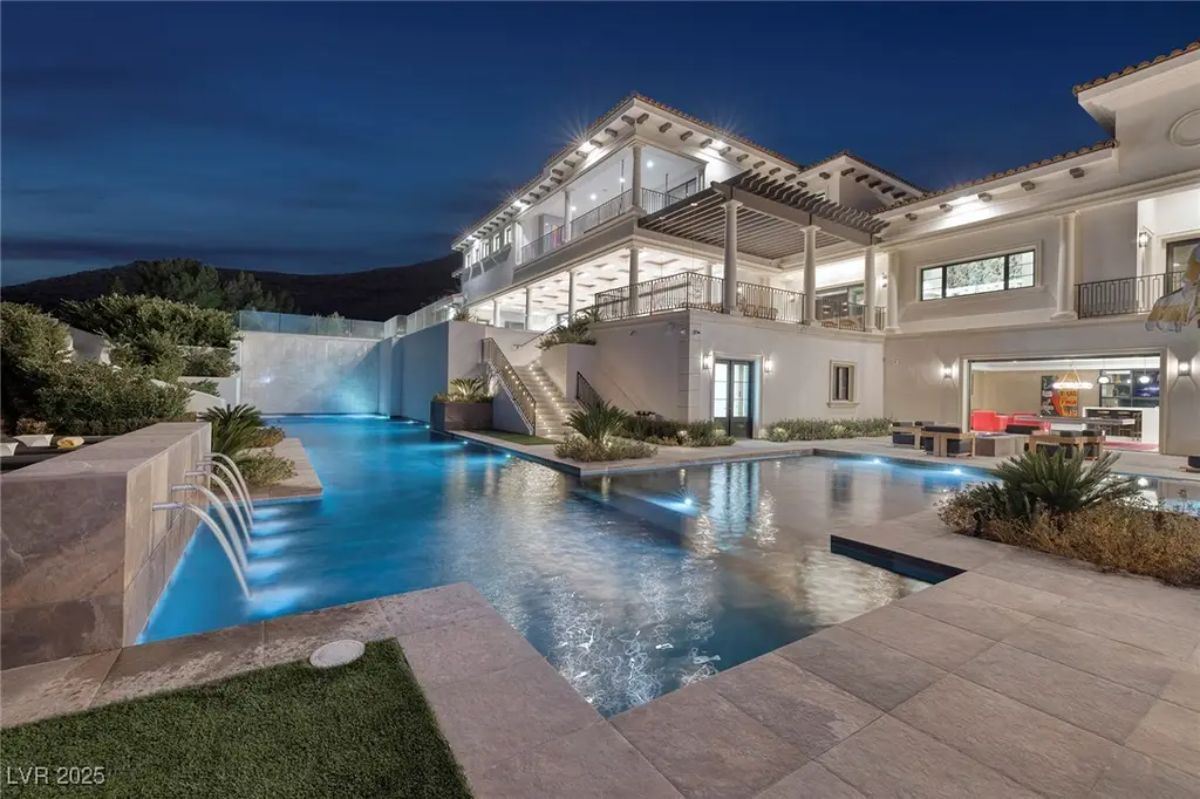 Multi-level swimming pool wraps around the exterior of the home with built-in waterfalls and an infinity edge.