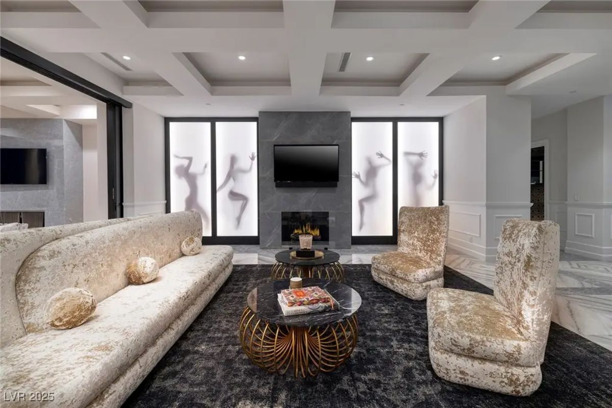 Seating area with fireplace and TV is framed by three frosted glass panels with abstract human figures.