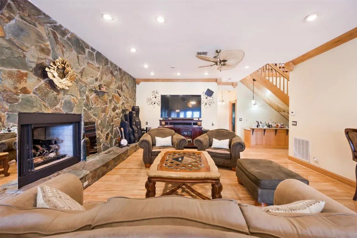 Open concept living room with a stone accent wall and double-sided fireplace.