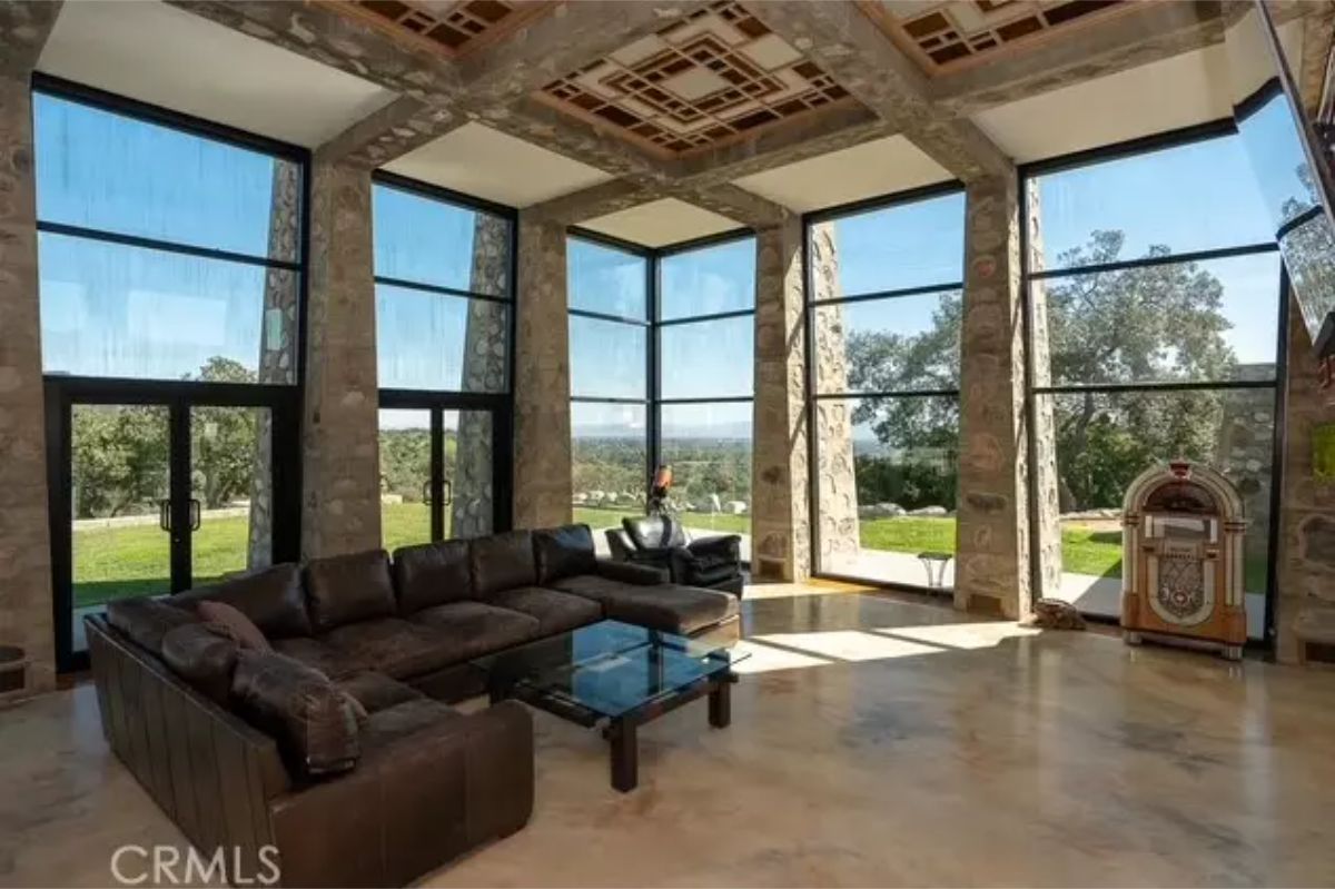 Living space features expansive floor-to-ceiling glass panels framed by stone columns.